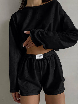 Black perforated crop top and shorts set with long sleeves and elastic waistband.