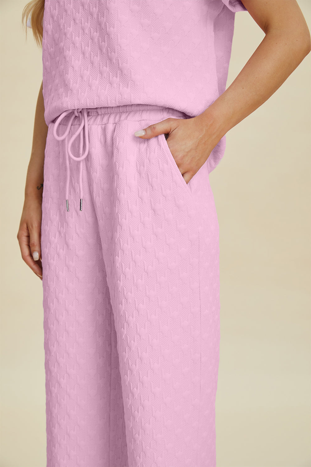 Pink textured knit lounge set with wide leg pants and drawstring waist.