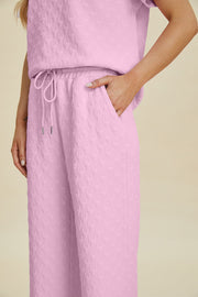 Pink textured knit lounge set with wide leg pants and drawstring waist.