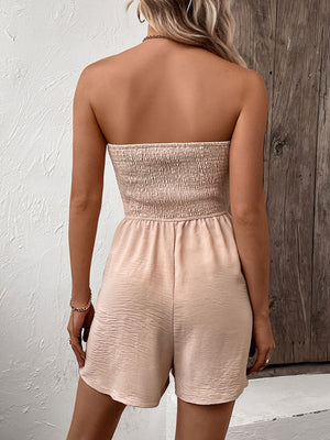 Tan smocked bodice strapless romper with tie-waist and textured shorts.