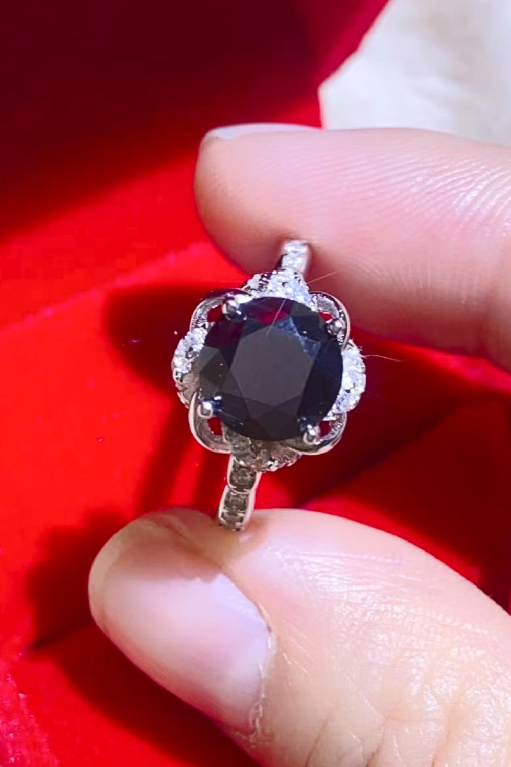 Black moissanite ring with a floral halo and pave band.