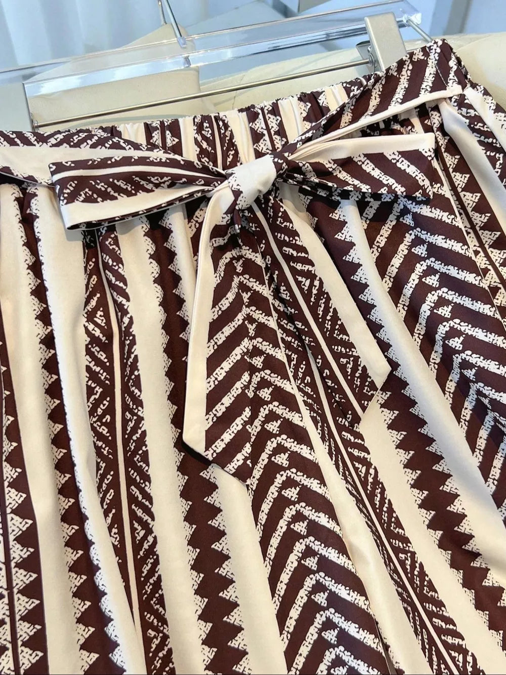 Maternity wide-leg pants in brown and white geometric print with a tie bow detail.