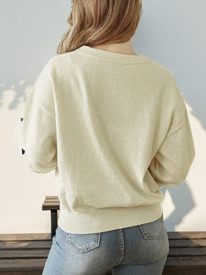 Cream acrylic sweater with scattered heart intarsia detail on balloon sleeves.