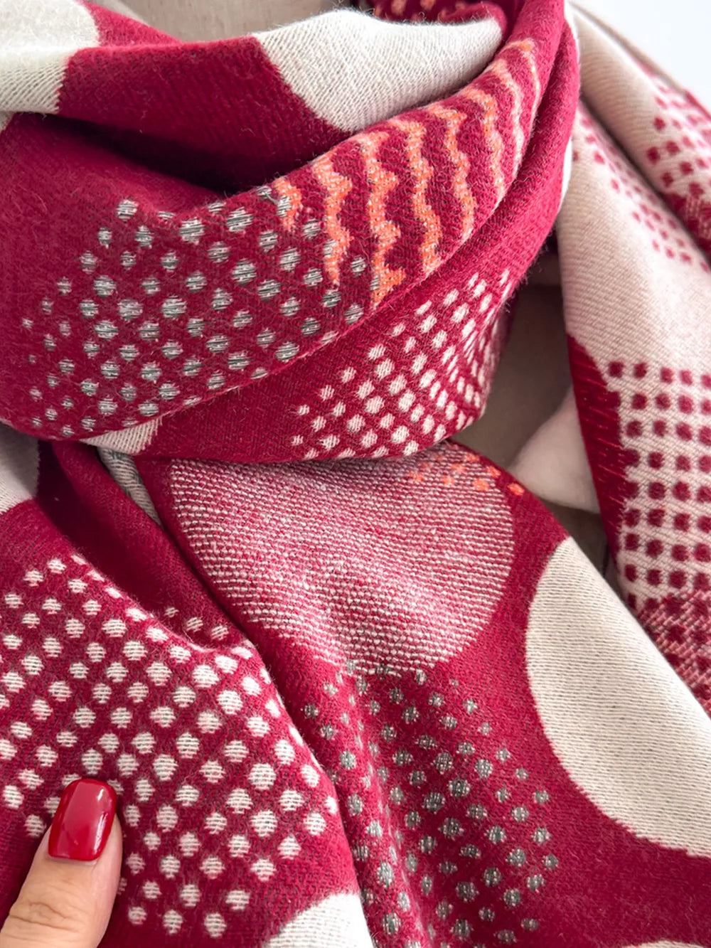 Deep red and cream textured scarf with polka dot and chevron patterns.