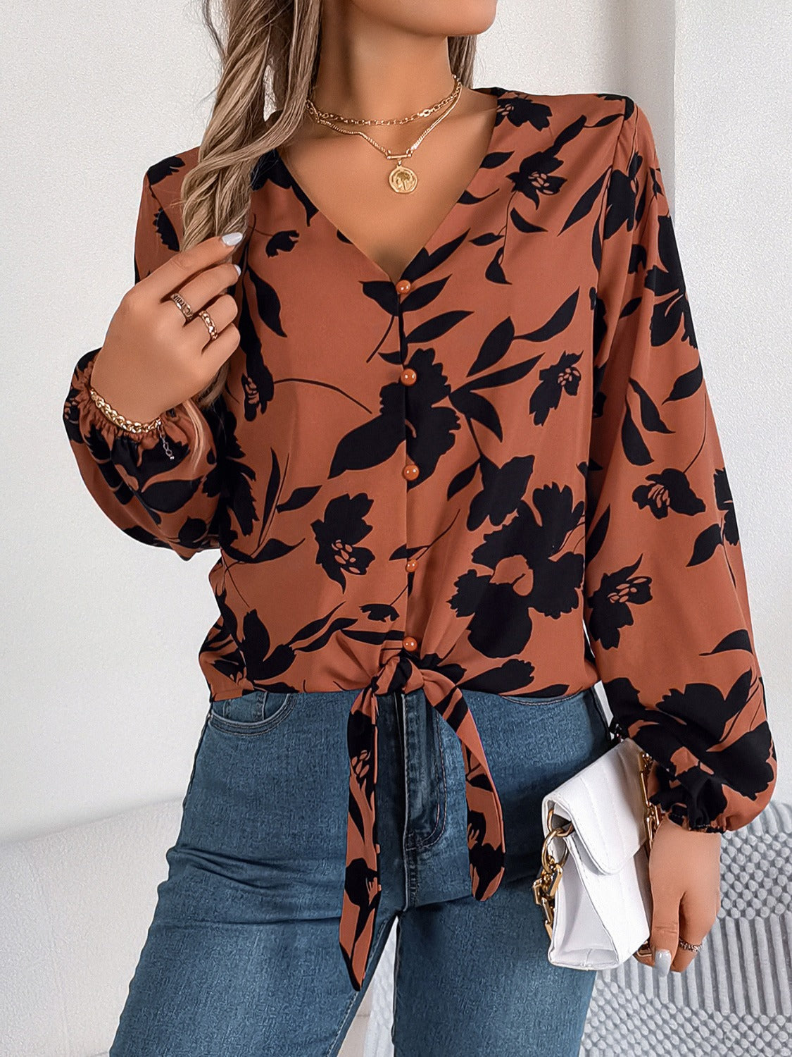 Brown floral knot-front blouse with V-neck and button detail.