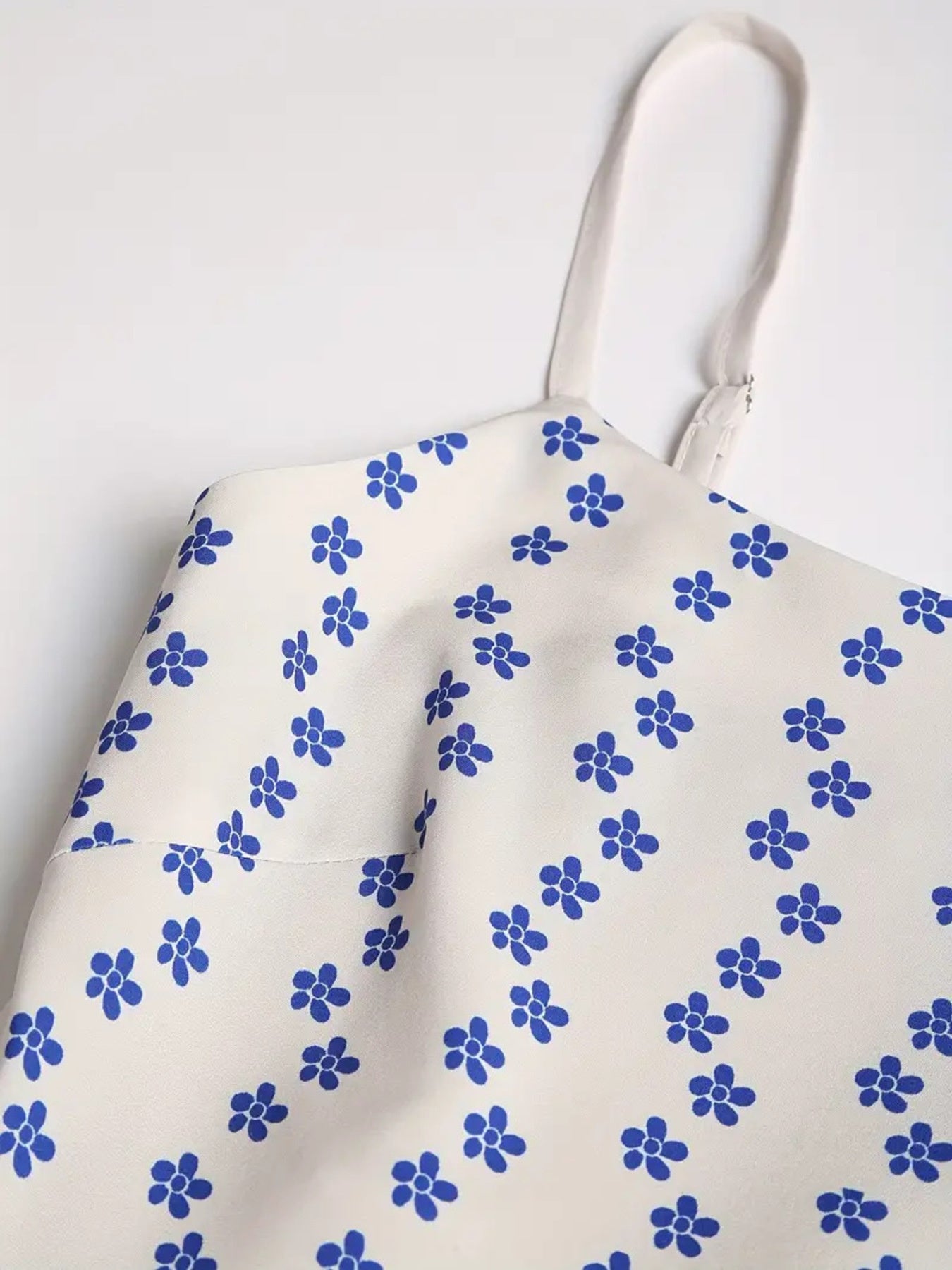 Spaghetti strap midi dress in cream with blue floral print and adjustable straps.