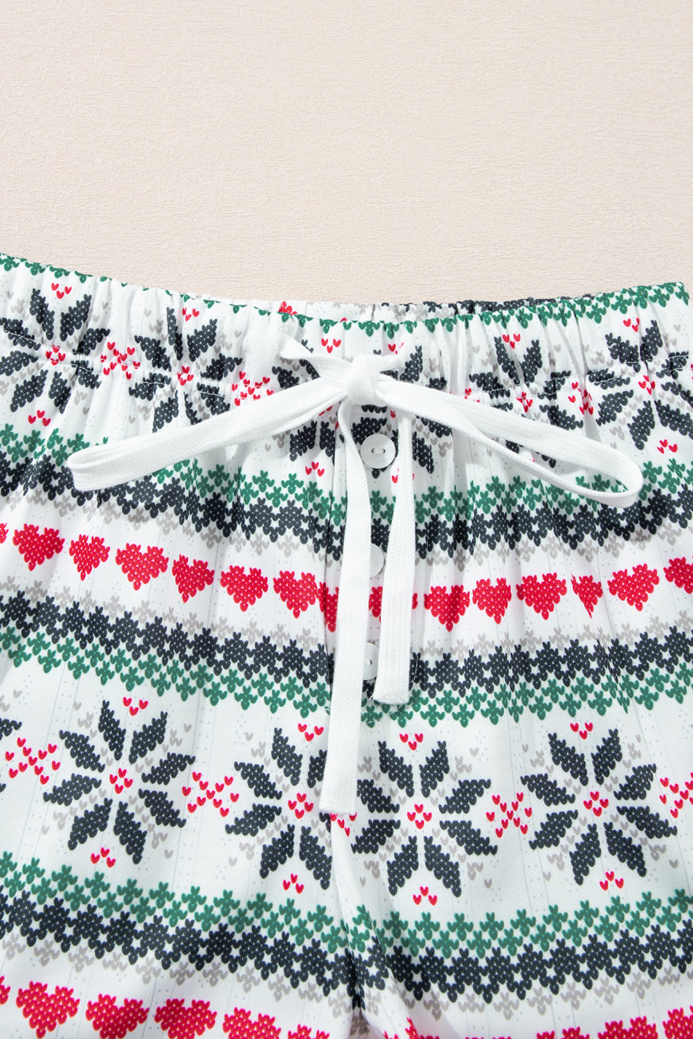 White cotton pajama shorts with festive snowflake and heart Fair Isle pattern, drawstring waist.