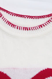 White knit sweater with red zigzag trim detail and festive bow graphic.