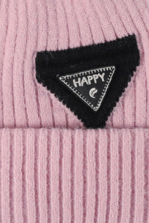 Pink ribbed acrylic beanie with black triangle patch featuring "HAPPY" text.