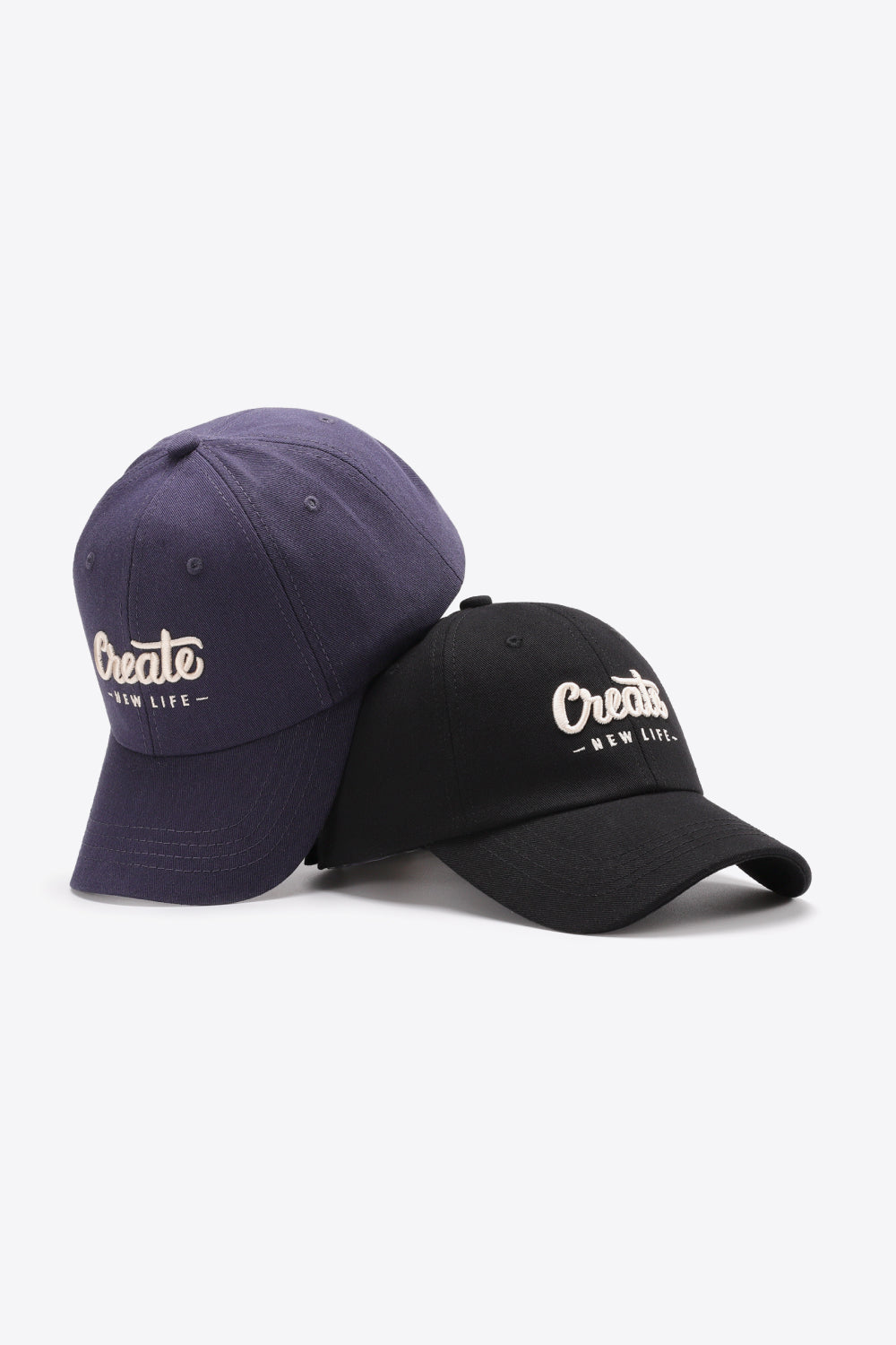 Navy and black baseball caps with white "Create New Life" embroidery.