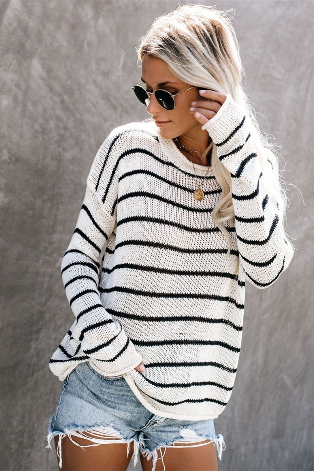 Relaxed white and black striped knit pullover sweater with crew neck.