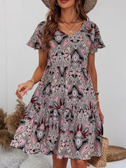 Paisley print mini dress with flutter sleeves and tiered skirt in cream, pink, and black.