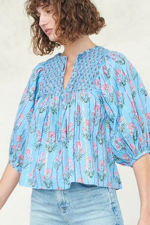 Sky blue floral print smocked yoke blouse with puff sleeves and metallic stripes.