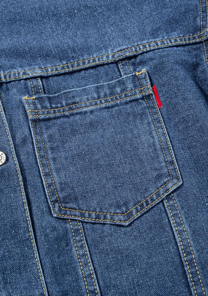 Denim trucker jacket in medium blue with yellow stitching and red tab detail.