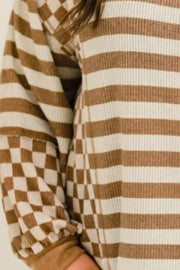 Brown and white striped waffle knit top with checkerboard sleeves.