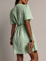 Light green textured V-neck ruched mini dress with short puff sleeves and cinched waist.