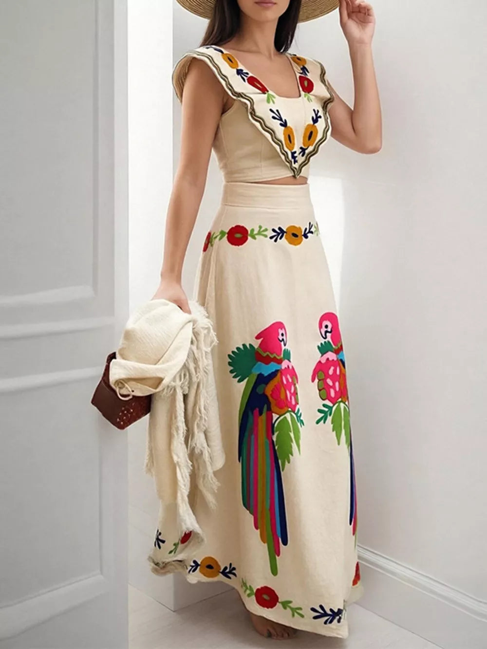 Cream embroidered crop top and maxi skirt with parrot and floral details.