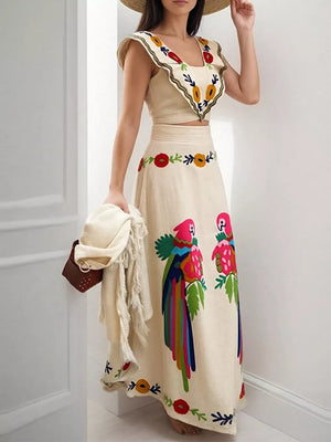 Cream embroidered crop top and maxi skirt with parrot and floral details.