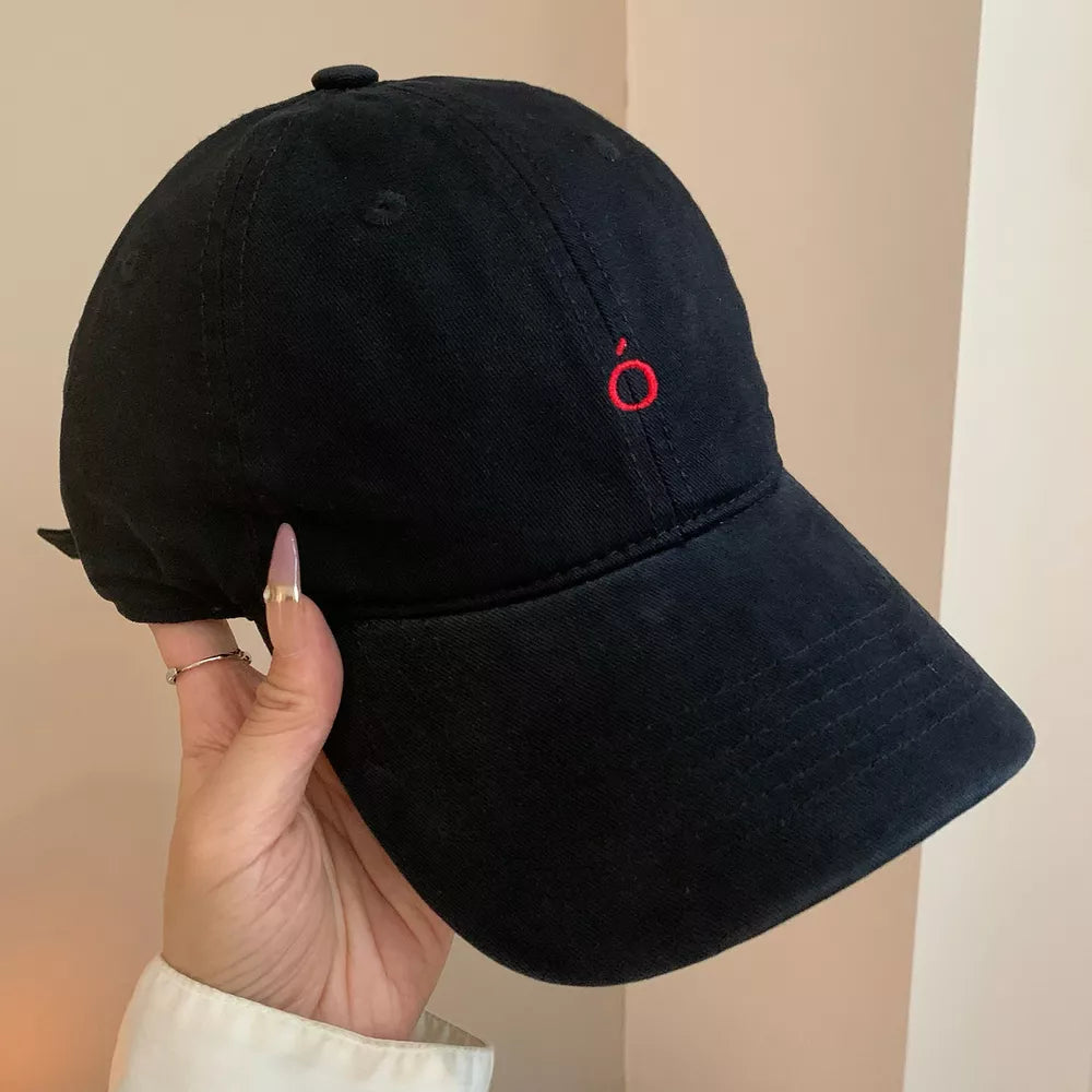Black cotton baseball cap with curved brim and red embroidered logo detail.