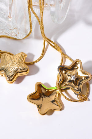 Gold starburst pendant necklace with textured and smooth star charms and a neon accent.