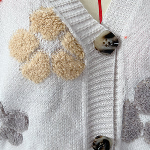 Ivory knit cardigan with embroidered floral details and tortoiseshell buttons.