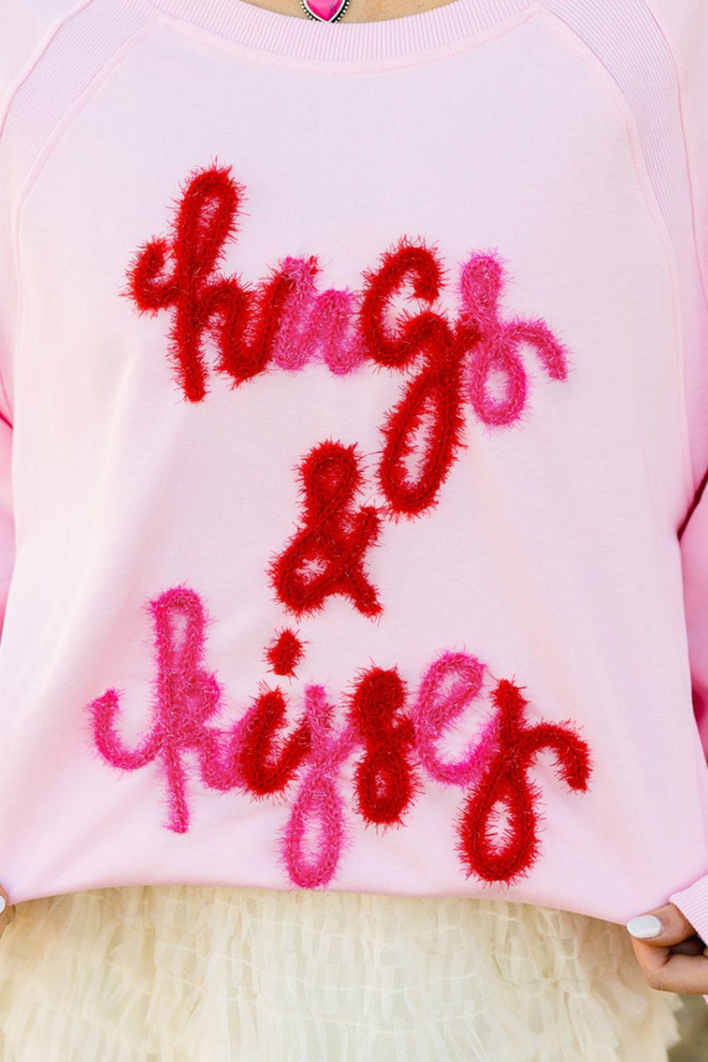Blush pink sweatshirt with fuzzy red and pink "hugs & kisses" embroidery