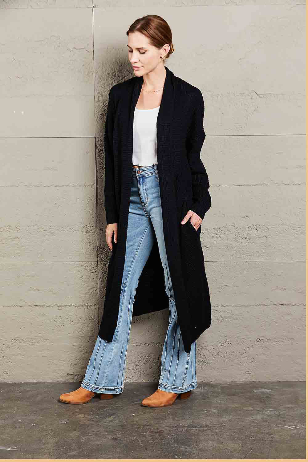 Black textured knit maxi cardigan with shawl collar and pockets, styled with jeans.