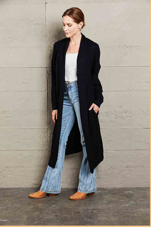 Black textured knit maxi cardigan with shawl collar and pockets, styled with jeans.