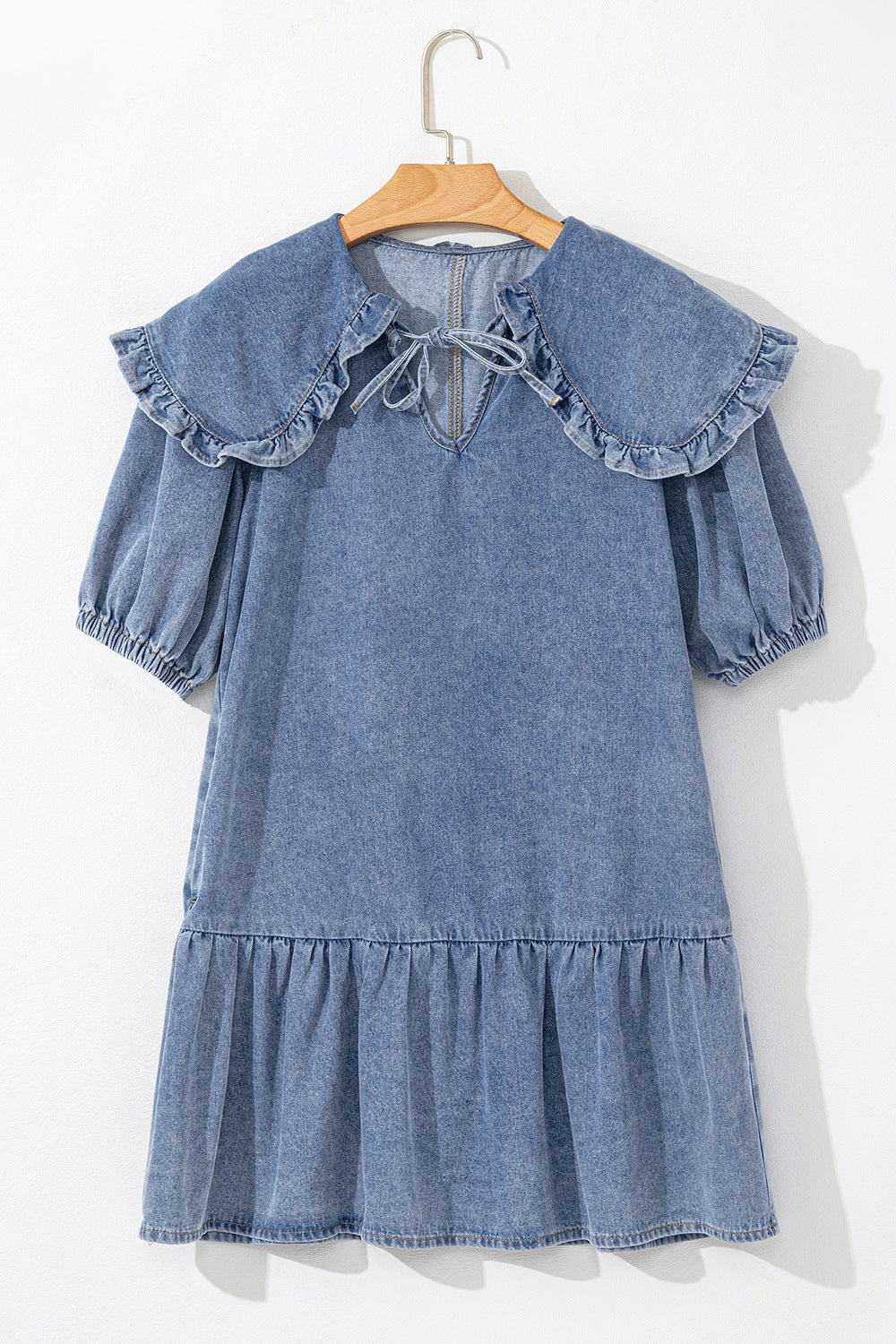 Denim mini dress with ruffle collar, tie neck, puff sleeves, and tiered ruffle hem.