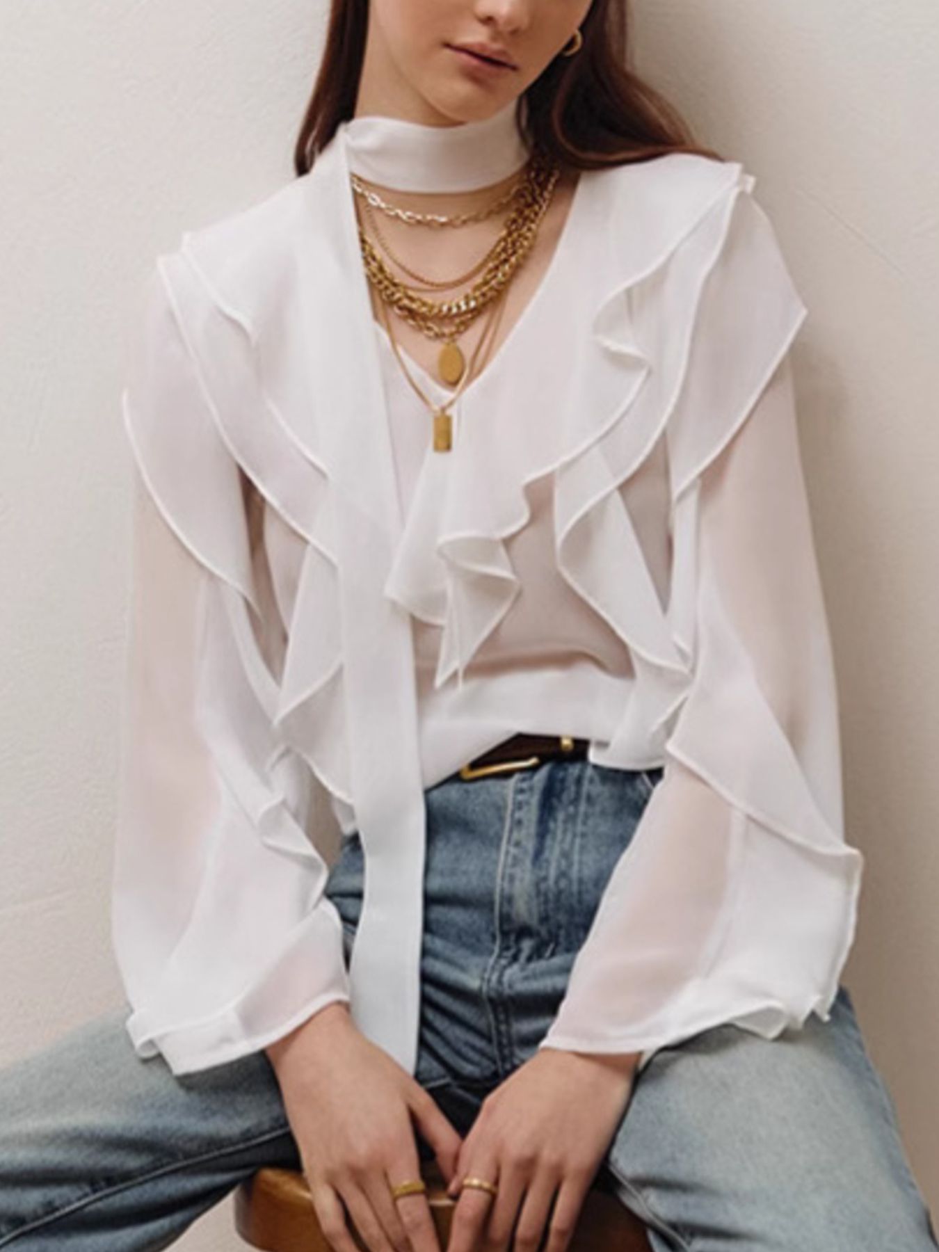 White chiffon blouse with V-neck, ruffle trim, and tie detail.