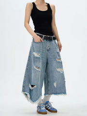 Distressed wide-leg jeans with raw hem and rips in light wash denim.