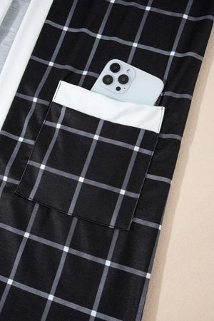 Black plaid duster cardigan with white trim and pocket detail, phone shown in pocket.