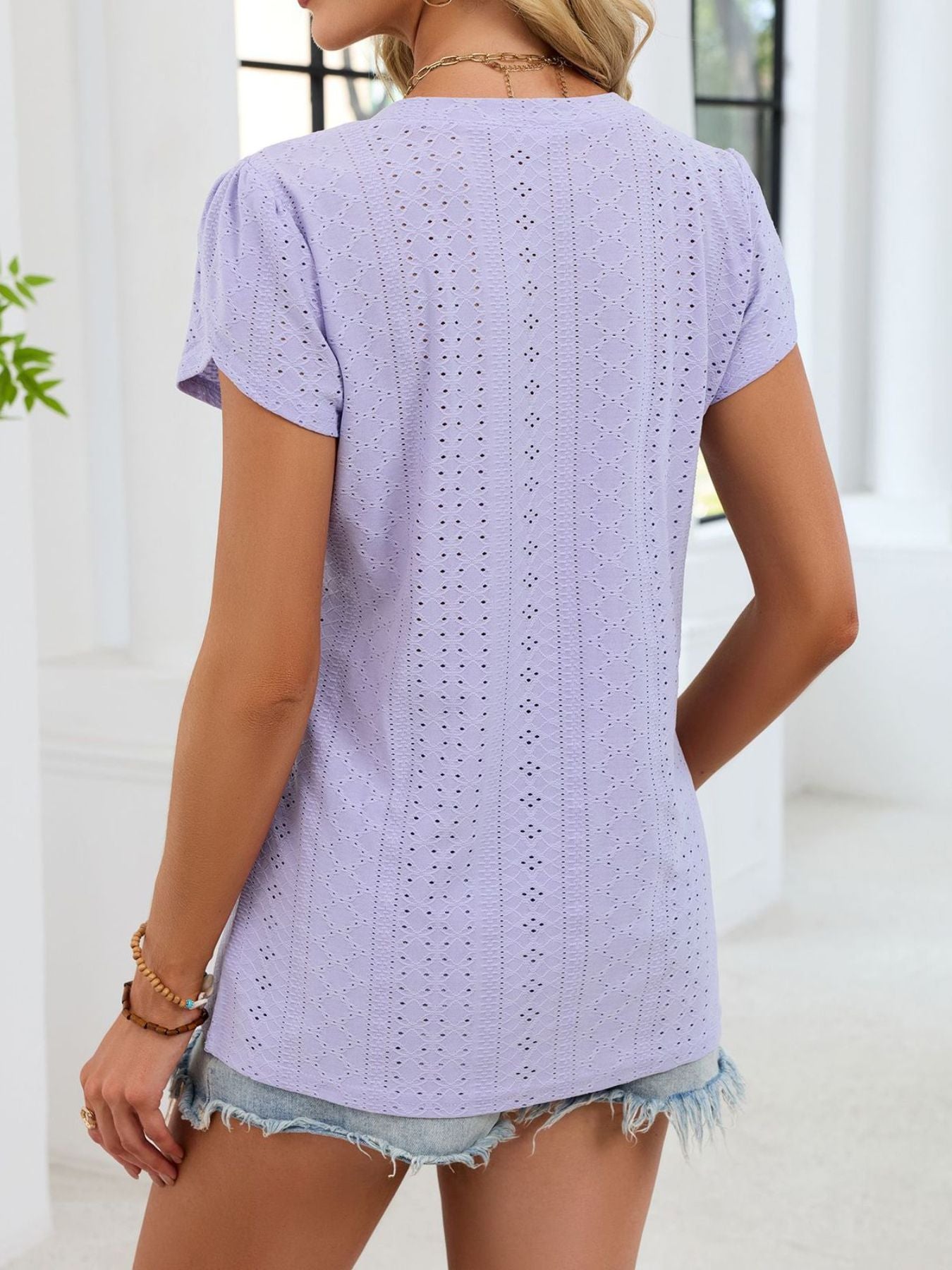 Lavender eyelet tee with petal sleeves and V-neck, featuring a textured pattern.