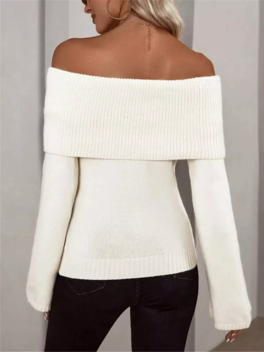White ribbed knit off-shoulder sweater with long sleeves.
