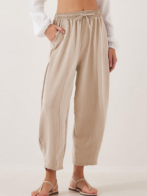 Tan balloon trousers with drawstring waist and sculpted seamlines.