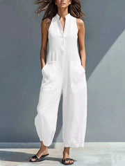 White sleeveless button-down romper with pockets and wide legs.