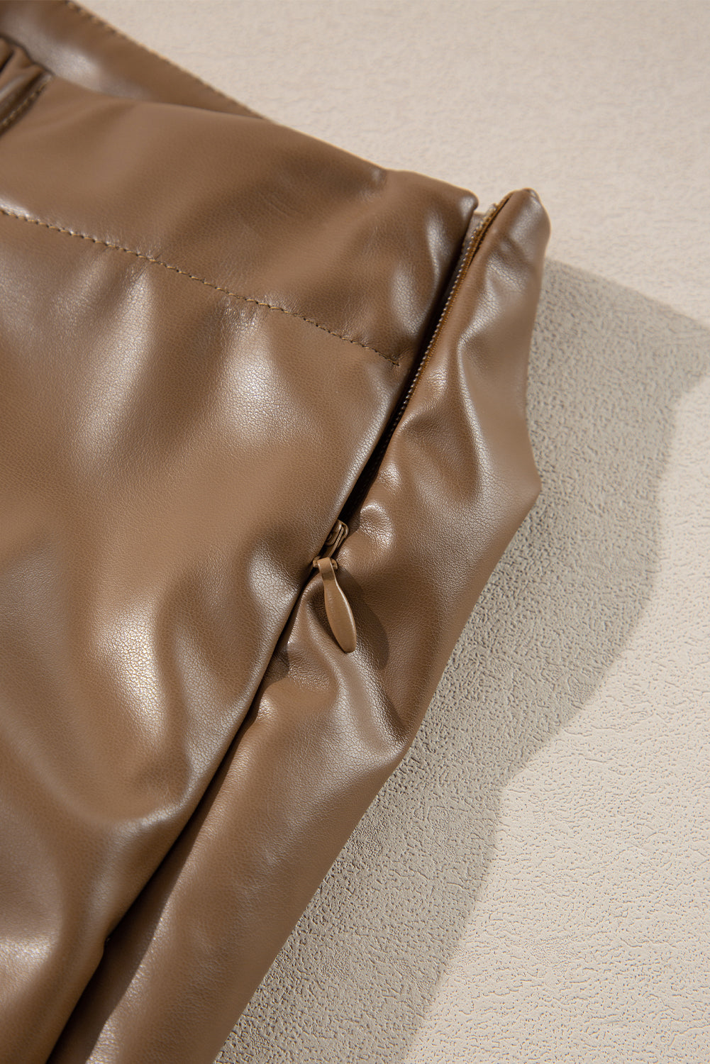 Brown faux leather mini skirt with knot detail and side zipper.