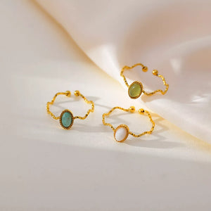 Wavy gold-plated rings with oval natural stones in cream, turquoise, and green styles.
