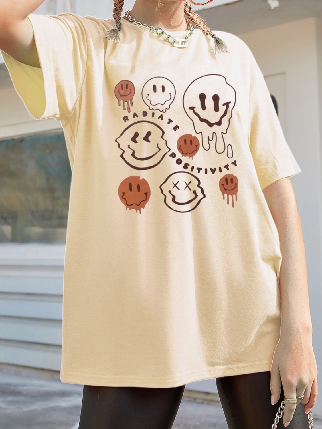 Tan oversized graphic tee with melting smiley faces and "Radiate Positivity" text.