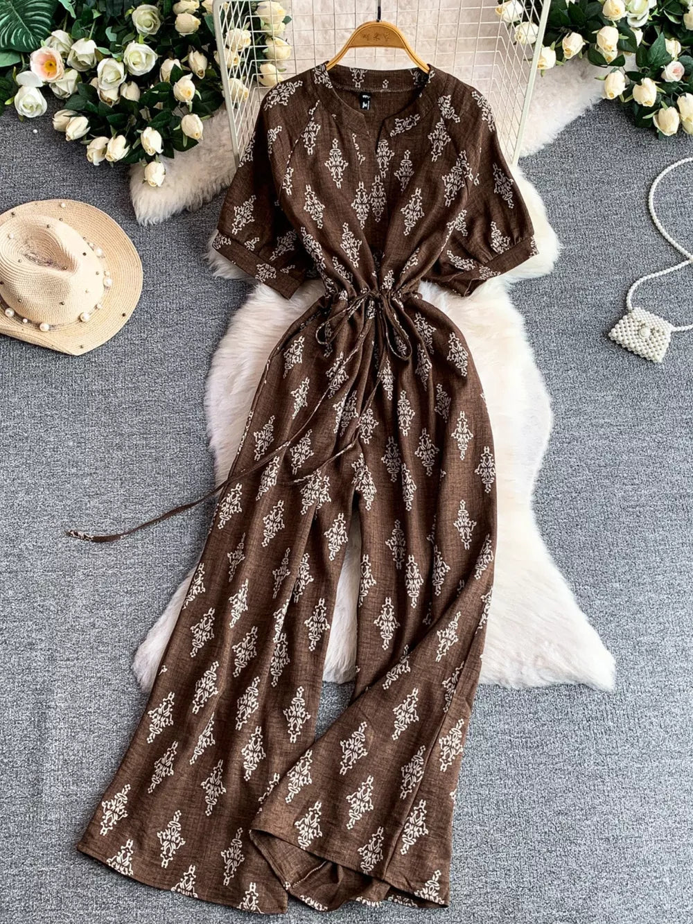 Brown patterned drawstring jumpsuit with short sleeves and wide legs.