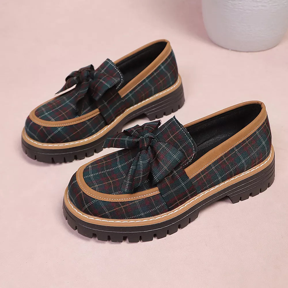 Plaid chunky loafers with bow accent in green and burgundy plaid with tan trim.