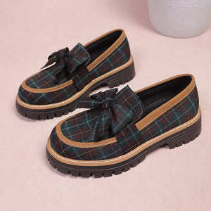 Plaid chunky loafers with bow accent in green and burgundy plaid with tan trim.