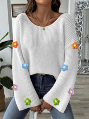 White knit sweater with colorful embroidered floral appliques on the sleeves.
