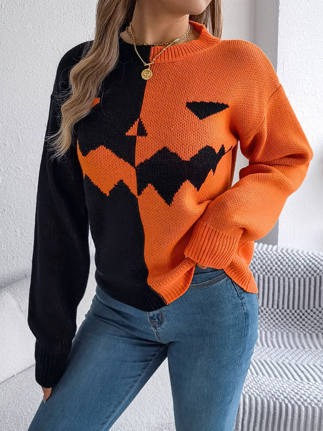 Split-face pumpkin knit sweater in orange and black acrylic with a crew neck and long sleeves.