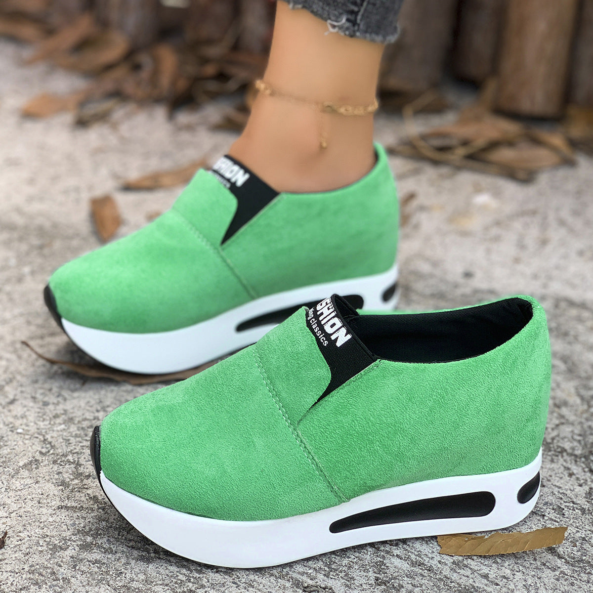 Green round toe slip-on sneakers with platform sole and black trim.