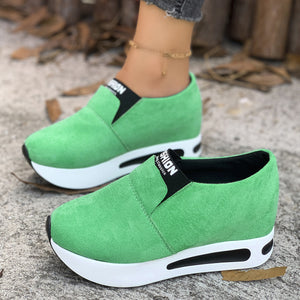 Green round toe slip-on sneakers with platform sole and black trim.