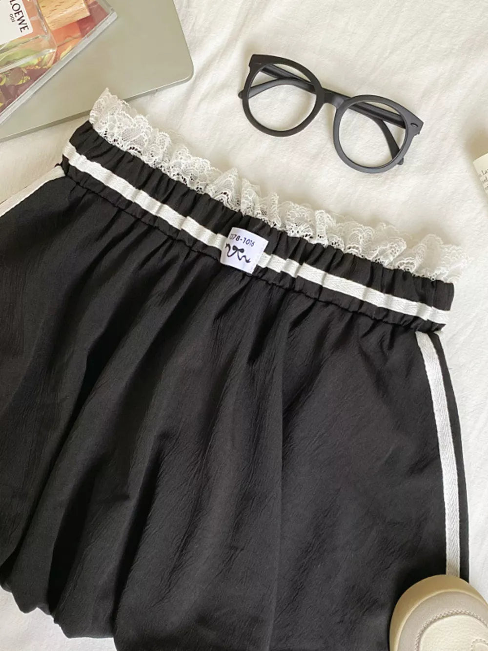 Black mini skirt with lace trim, gathered waist, and white side stripes.