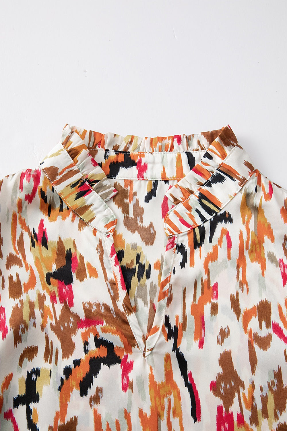 Blouse with abstract print, ruffled collar, and V-neck.