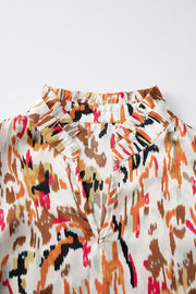 Blouse with abstract print, ruffled collar, and V-neck.