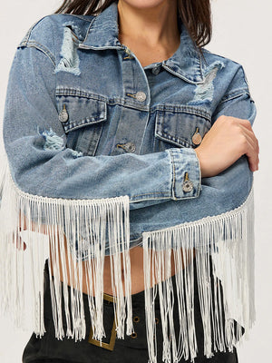 Distressed denim trucker jacket in medium wash with white fringe trim and distressed details.